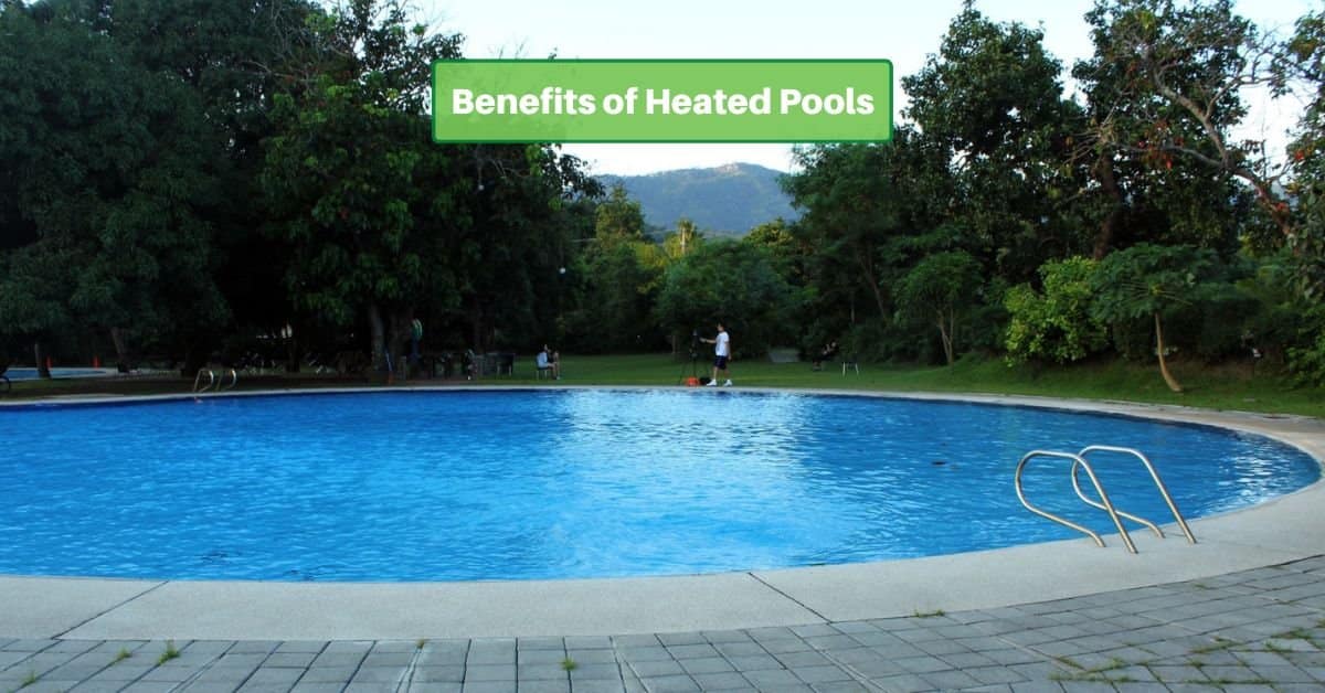 A swimming pools with a stone deck, trees in the background. Text reads, benefits of heated pools
